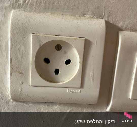 שקע חשמל על קיר לבן עם סימני לכלוך